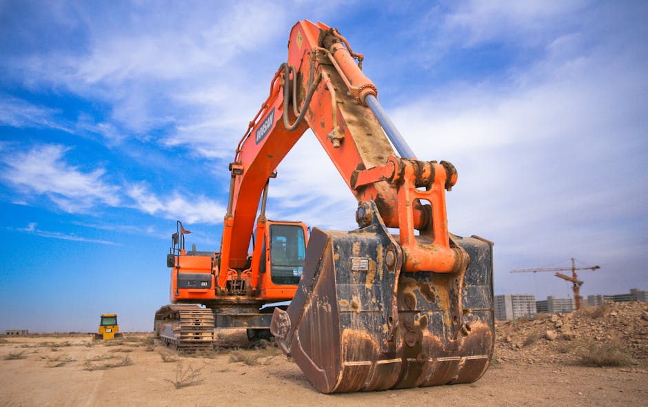 A large orange excavator working on a construction site under a blue sky