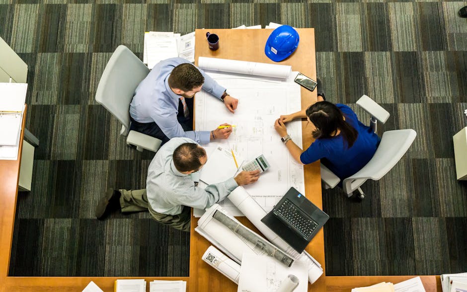 Top view of a team working on construction plans in an office setting