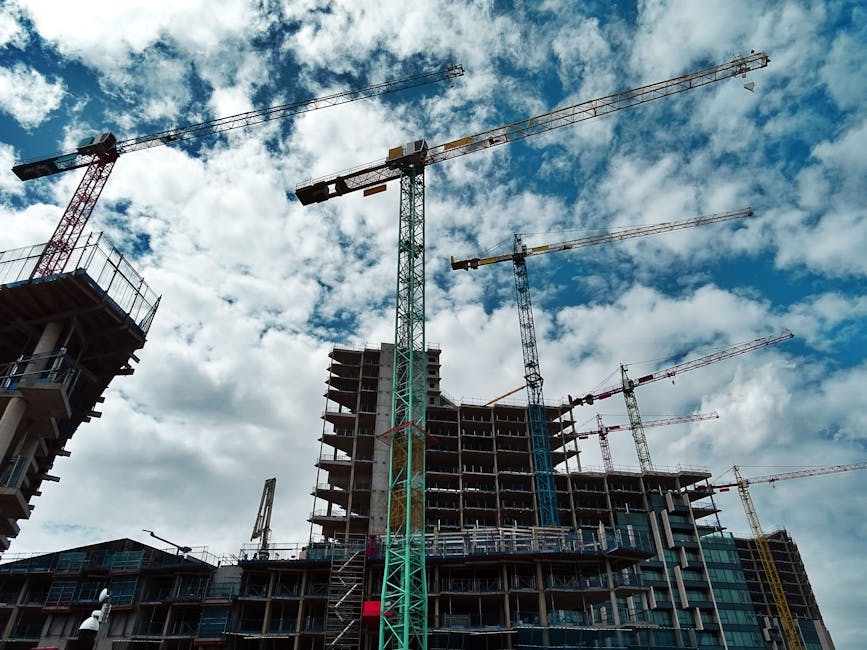 Urban construction site with numerous cranes framing rising skyscrapers against a blue sky